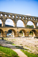Fototapeta na wymiar Vertical picture of roman aqueduct Pont du Gard, Unesco World Heritage site. Located near Nimes, Languedoc, France, Europe. Stone big roman arch. Travel tourism destination in Provence