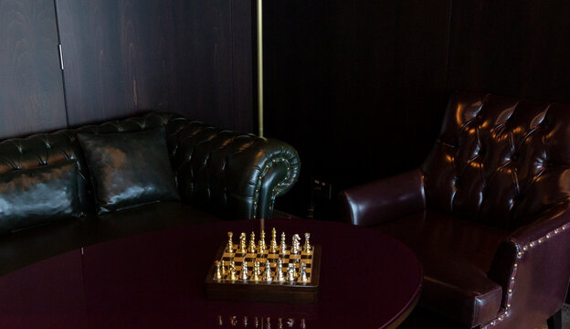 Golden chess on the table with leather chair and it's ready to play
