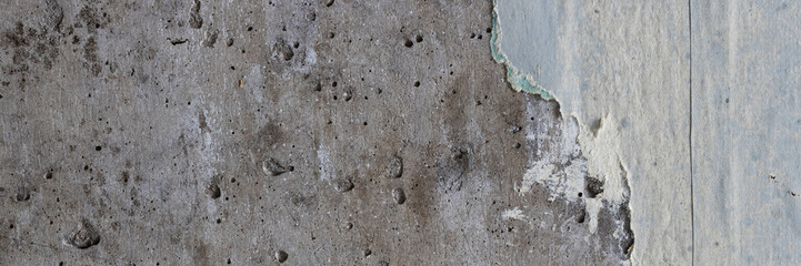 Torn old faded paper wallpaper on a concrete wall. Ragged scraps of paper on a gray background. Vintage texture for background and design. Closeup view with copy space for text.