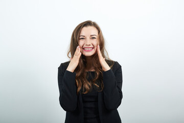 Touching her cheeks with hand and smiling, smooth, flawless skin, young attractive woman brunette in a black t-shirt, sweater on white background