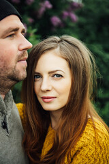 Fototapeta premium Beautiful couple in love is hugging near a lilac bush. lifestyle photo