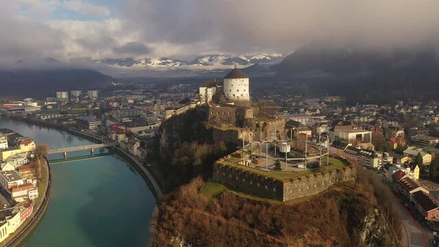 Aerial view of mountain town Kufstein with medieval hilltop fortress, dramatic winter scenery at sunrise, river Inn meandering through the valley - Austrian Alps from above, Tyrol, Austria, Europe