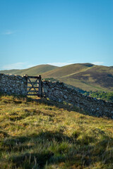 A Gate in a Stone Wall On a Path in Remote Scottish Countryside With Hills and a Castle in the Background