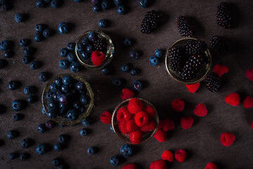 close up of wet raspberry, blueberries and blackberries in small bowls