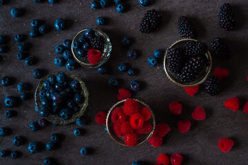 close up of wet raspberry, blueberries and blackberries in small bowls