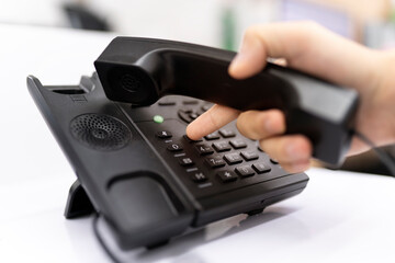 Close-up Of A Businessman's Hand Dialing Telephone Number To Make Phone Call In Office, contact us and customer relations support The concept of a telephone number keypad for communication.