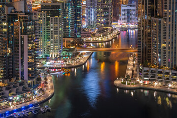 Dubai Marina promenade and water canal at night. Aerial view of Dubai skyscrapers.