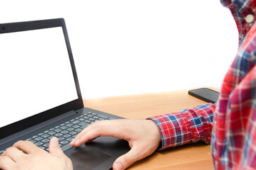 A man at a laptop. A guy in a checkered red shirt sits at a table and works on a laptop, typing. White screen laptop