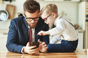businessman father with a young schoolboy son looking at a smartphone.