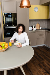 surprised man chatting on smartphone during breakfast in kitchen