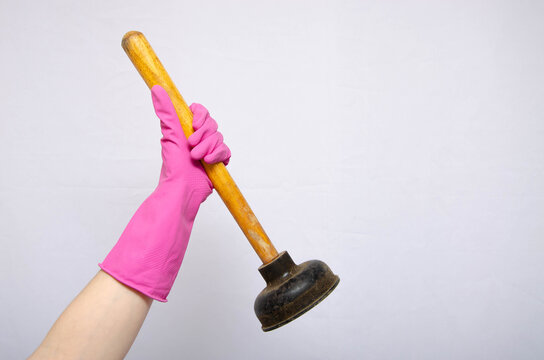 Vantus. Female hands in pink gloves hold a large plunger for cleaning pipes, blockages. Vantus with a wooden handle. Vantus in hands and gloves