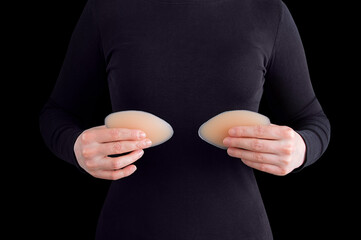 Silicone push up in the hands of woman close-up on black background.