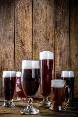 Different sorts of craft beer on wooden bar background. Set of various beer glasses and mugs. Beer tasting concept