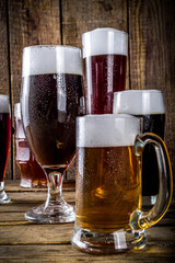 Different sorts of craft beer on wooden bar background. Set of various beer glasses and mugs. Beer tasting concept