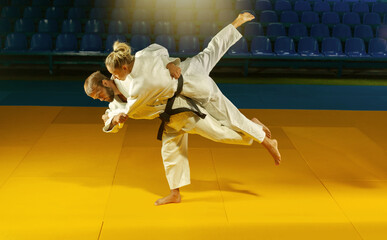 Martial arts. Sparing Portners. Sport man and woman in white kimono train judo throws and captures...