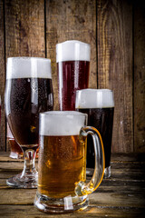 Different sorts of craft beer on wooden bar background. Set of various beer glasses and mugs. Beer tasting concept