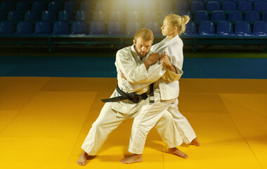 Martial arts. Sparing Portners. Sport man and woman in white kimono train judo throws and captures...