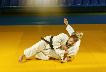 Martial arts. Sparing Portners. Sport man and woman in white kimono train judo throws and captures...