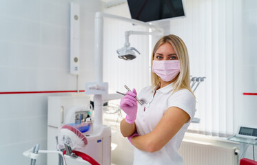 Female doctor holding dental instruments in hands. Doctor's portrait. Medical help, prophylaxis or insurance concept. Health, protection and prevention.