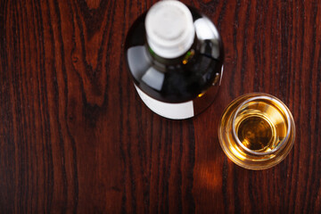 Bottle and glass of whisky spirit brandy on dark brown background