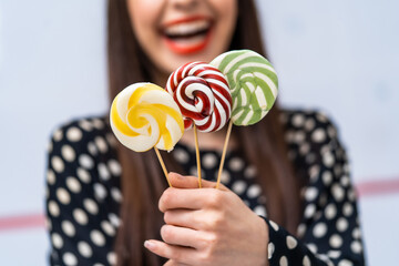 Female hand with sweet lollipops on blurred background. Hand holding lollipop isolated on white...