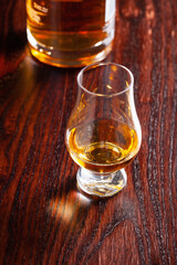 Bottle and glass of whisky spirit brandy on dark brown background