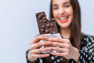 Lady showing chocolate bar with nuts to the camera. Sweet life concept.