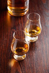 Bottle and glass of whisky spirit brandy on dark brown background