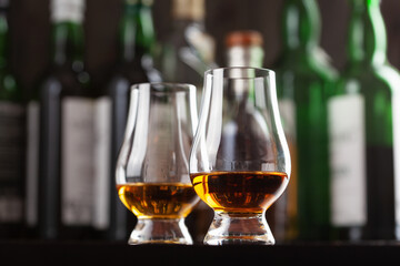 Bottles and glass of whisky spirit brandy on dark brown background