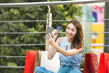 Young adult asian woman use online payment by credit card and smart phone.