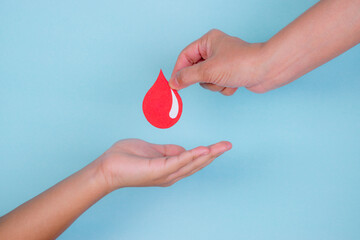 Woman hand gives a red blood drop to a boy hand for blood donation concept,World blood donor day. Copy space for advertisers.