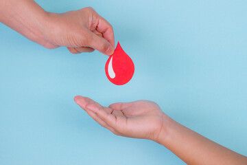 Woman hand gives a red blood drop to a boy hand for blood donation concept,World blood donor day....