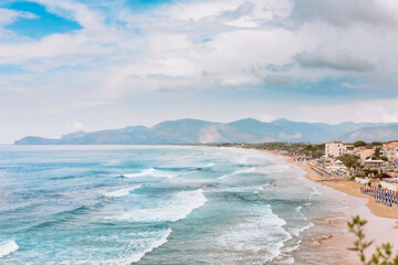 Desert beach in Sperlonga, Italy. Waves at sea. Mountains in the background.