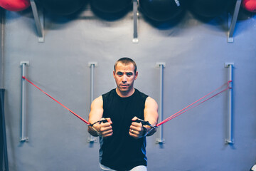 Latin boy looking at camera doing arm strength exercises with elastic bands