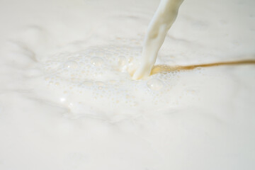 Drops of liquid milk pouring down or white drops with ripples
