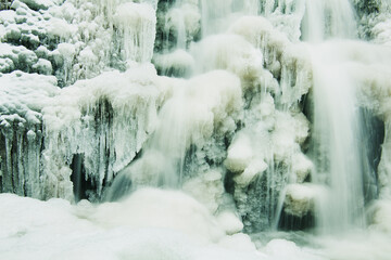 Winter waterfall, frozen water and water flowing on the ice surface, winter background.