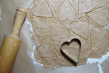 Heart shaped cookie cutters cutting out holiday cookies.