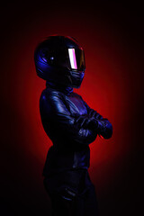 Portrait of a young female biker wearing a leather jumpsuit and a black helmet