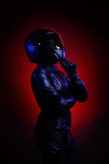 Portrait of a young female biker wearing a leather jumpsuit and a black helmet