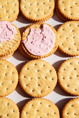 Sandwich cookies with pink strawberry cream filling on white background. Trendy minimal food. Simple bakery, top view