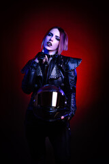 Portrait of a young sexy biker woman wearing a studded leather jacket and black helmet