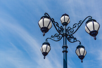 Fototapeta na wymiar Decorative retro street lamp or lamppost on blue sky background