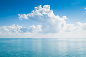 Naklejka na ściany i meble White fluffy clouds and turquoise sea on blue sky