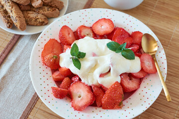 Fresh strawberries with cream and sugar on a plate.