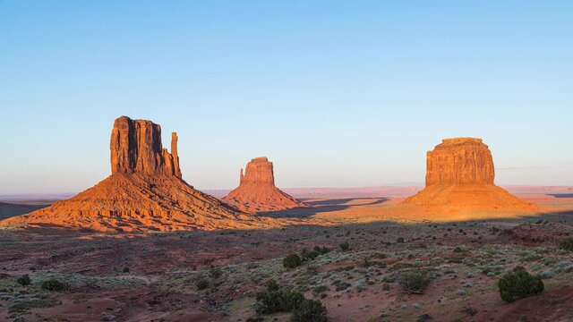 Timelapse time lapse view of famous east West mittens and Merrick buttes at horizon in Monument Valley at sunset twilight evening colorful light in Arizona, USA with orange canyon rock formations