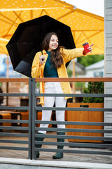 A young pretty teenage girl walks around the city in rainy weather. The girl is dressed in colored clothes and rubber boots