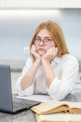 Pensive unhappy girl looks at camera at home. Distance learning concept