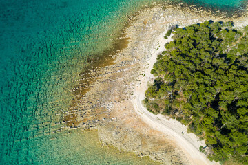 Aerial view of the rocky coast with the pebble beach and pine forest near Pakostane in Dalmacija
