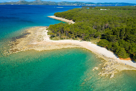 Aerial view of the rocky coast with the pebble beach and pine forest near Pakostane in Dalmacija