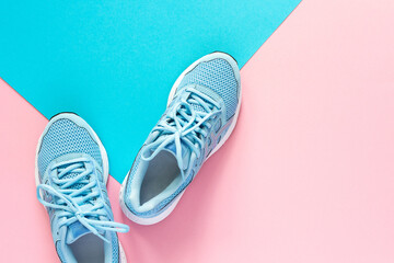 Blue sneakers isolated on pink and blue background, seasonal shoes for walking and sports, copy space, top view